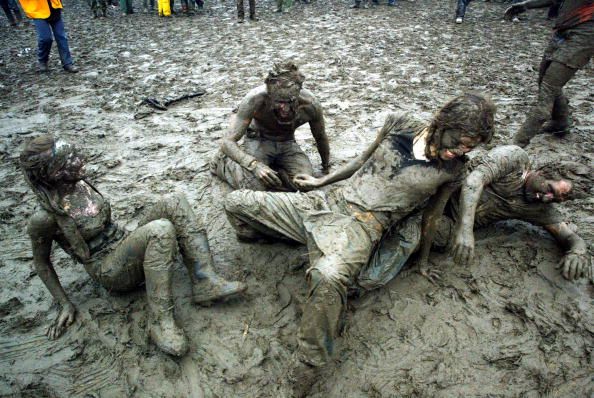SOMERSET, ENGLAND - JUNE 26:  Festival-goers dance in the mud in front of the Pyramid stage at Worthy Farm, Pilton, Somerset, at the 2004 Glastonbury Festival, 26 June 2004. The festival spans over 3 days and runs until June 27.   (Photo by Matt Cardy/Getty Images)