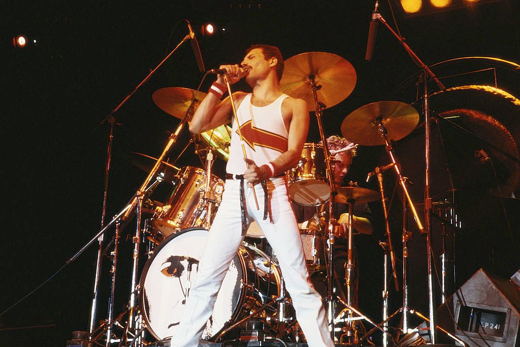 Freddie Mercury (1946-1991), singer with Queen, standing in front of a drumkit as he sings into a microphone on stage during a live concert performance by the band at the National Bowl in Milton Keynes, England, United Kingdom, on 5 June 1982. (Photo by Fox Photos/Hulton Archive/Getty Images)