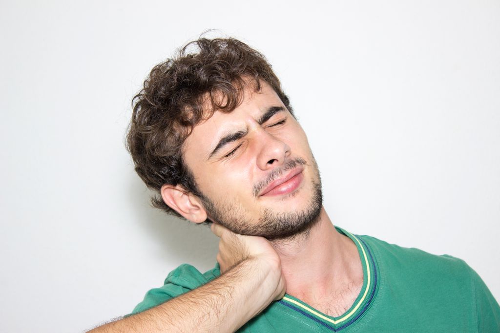 Front view of young man holding his neck in pain