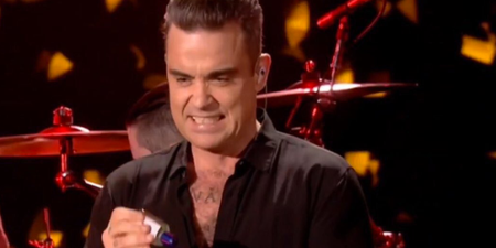 Watch a grimacing Robbie Williams use hand-sanitiser after touching audience at NYE gig