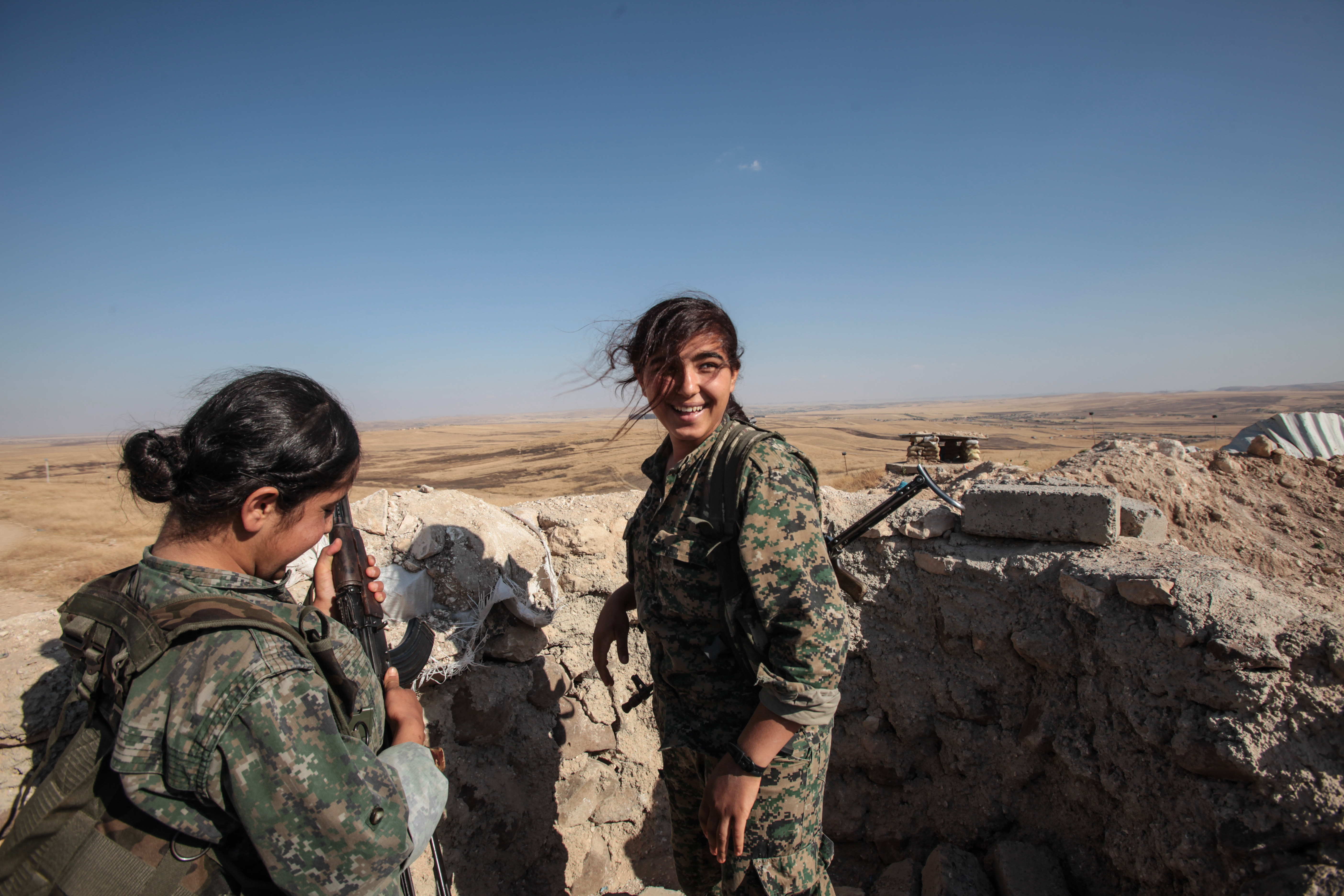 Kurdish People's Protection Units, or YPG's women fighters pose as they stand in a check point with their AK-47 at the outskirts of the destroyed Syrian town of Kobane, also known as Ain al-Arab, Syria. June 20, 2015. Kurdish fighters with the YPG took full control of Kobane and strategic city of Tal Abyad, dealing a major blow to the Islamic State group's ability to wage war in Syria. Mopping up operations have started to make the town safe for the return of residents from Turkey, after more than a year of Islamic State militants holding control of the town. (Photo by Ahmet Sik/Getty Images)