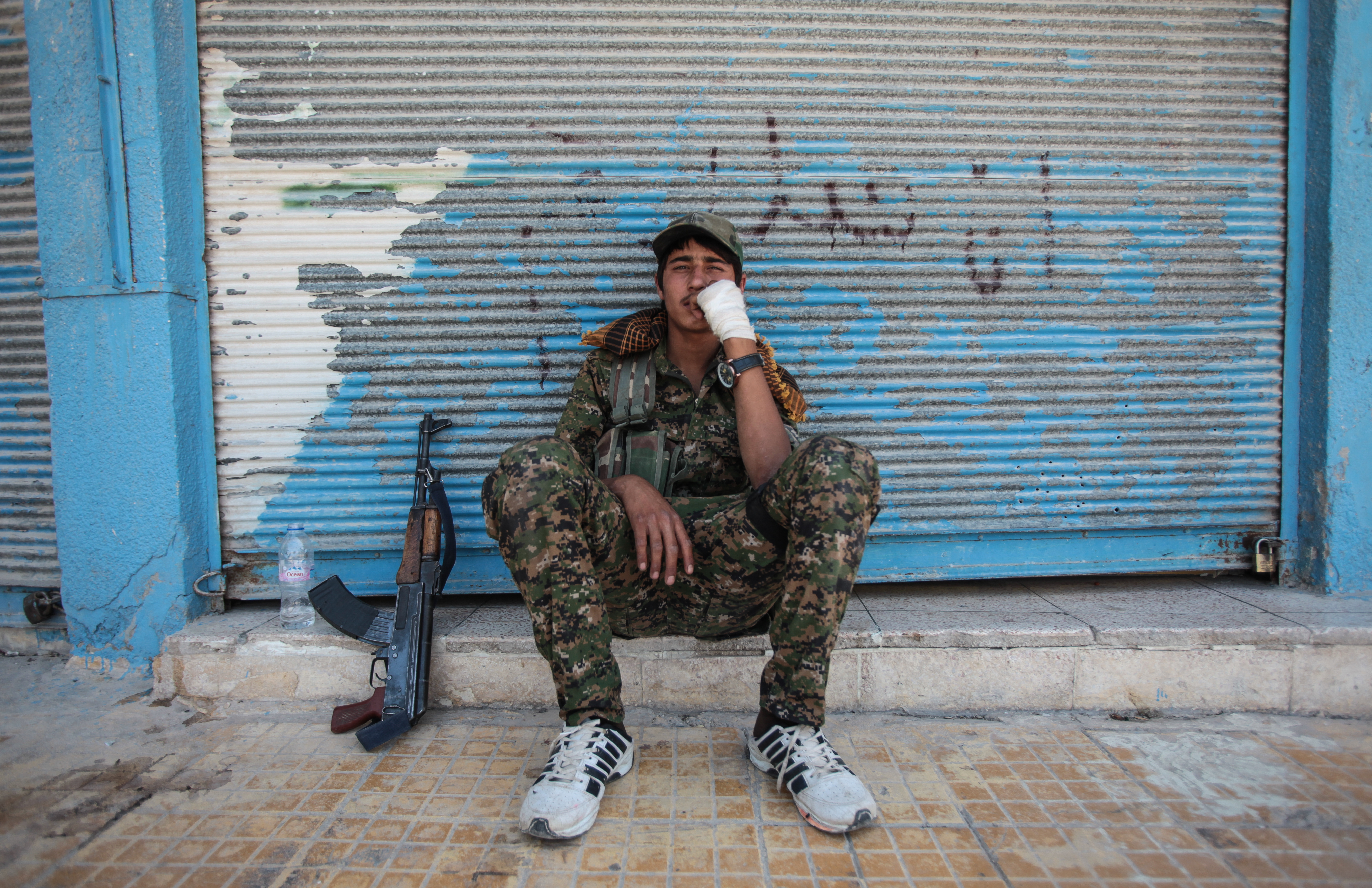 A wounded Kurdish People's Protection Units, or YPG fighters rests at downtown of Tal Abyad, Syria. June 19, 2015. Kurdish fighters with the YPG took full control of Tal Abyad, dealing a major blow to the Islamic State group's ability to wage war in Syria. Mopping up operations have started to make the town safe for the return of residents from Turkey, after more than a year of Islamic State militants holding control of the town. (Photo by Ahmet Sik/Getty Images)