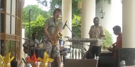 Man convinces African jazz band he can play the saxophone. He really, really can’t