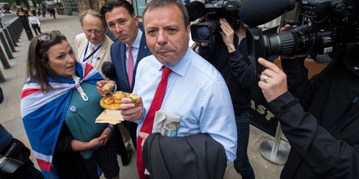 LONDON, ENGLAND - JUNE 12: Leave.EU backer Arron Banks eats a pork pie handed to him by an anti-Brexit demonstrator as he arrives to give evidence to the fake news select committee at Portcullis House on June 12, 2018 in London, England. The Digital, Culture, Media and Sport Committee are questioning Arron Banks and Andy Wigmore, of the pro-Brexit Leave.EU, as part of its inquiry into fake news. British Newspapers have revealed a series of meetings with Russia's UK Ambassador in the lead up to the Brexit Referendum. (Photo by Chris J Ratcliffe/Getty Images)