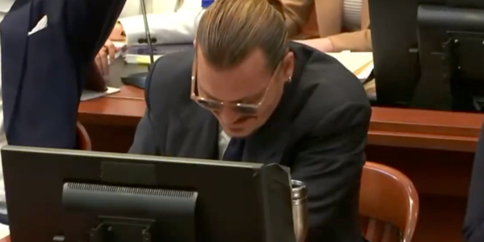 Johnny Depp smiling as Amber Heard's lawyer imitates his voice
