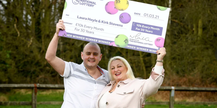 Kirk Stevens and Laura Hoyle are all smiles while holding up a big fake cheque after winning the National Lottery's 'Set For Life' draw in 2021