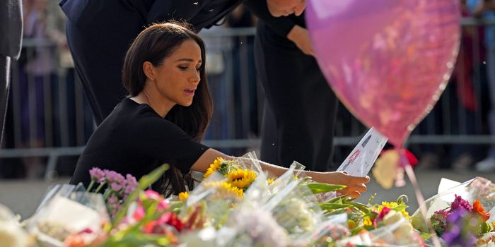 WINDSOR, ENGLAND - SEPTEMBER 10: Meghan, Duchess of Sussex and Prince William, Prince of Wales view floral tributes left at Windsor Castle on September 10, 2022 in Windsor, England. Crowds have gathered and tributes left at the gates of Windsor Castle to Queen Elizabeth II, who died at Balmoral Castle on 8 September, 2022. (Photo by Kirsty O'Connor - WPA Pool/Getty Images)